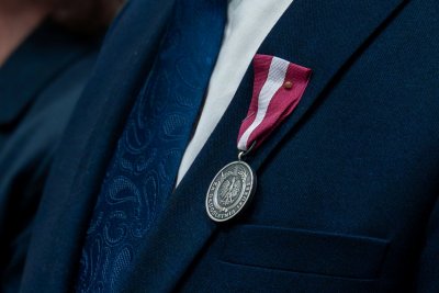 Medal przypięty do klapy granatowej marynarki.