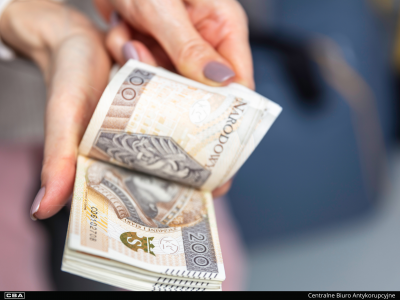 Zwój banknotów o nominale 200 zł w kobiecych dłoniach.
