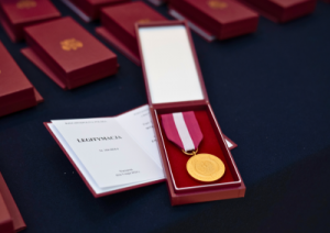 A golden medal in a red box. An open Identification Booklet. More medal boxes in the background.