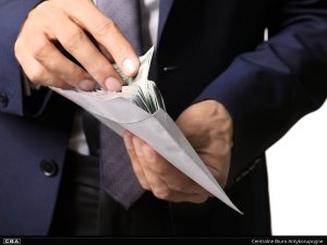 A man in a suit putting cash into an envelope.