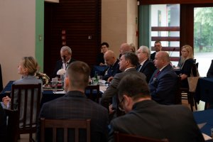 The attendees sit at tables and listen to the speech