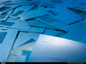 A sheet of paper with the caption: ‘VAT invoice’. A stack of envelopes in the background.