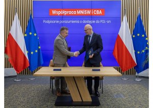 Minister of Science Dariusz Wieczorek and Deputy Head of CBA Dariusz Drozdowski shake hands. An inscription ‘Cooperation between MNiSW and CBA. Signing of the POL-on access agreement’ in the background.