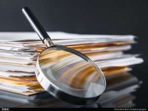 A photo of a magnifier and a pile of documents.