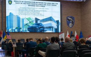 A photo of the audience. Screen with presentation in the background.