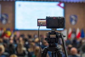 A camera photo. Audience and screen in the background.