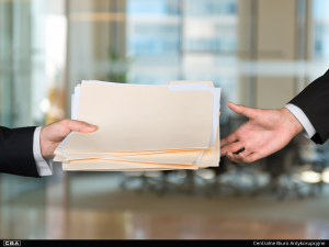 two people passing documents to each other