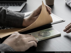 A man passing an envelope on the table with Polish banknotes underneath.