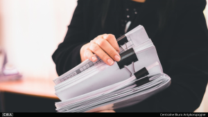 A woman dressed in suit holding documents.
