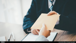 Two men handing an envelope to each other.
