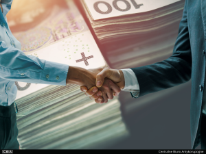 Men shakingd hands, polish banknotes in the background.